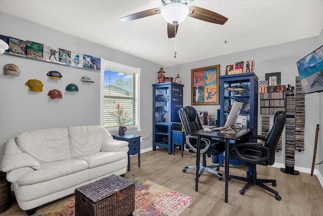 home office with ceiling fan, light wood-type flooring, and a textured ceiling