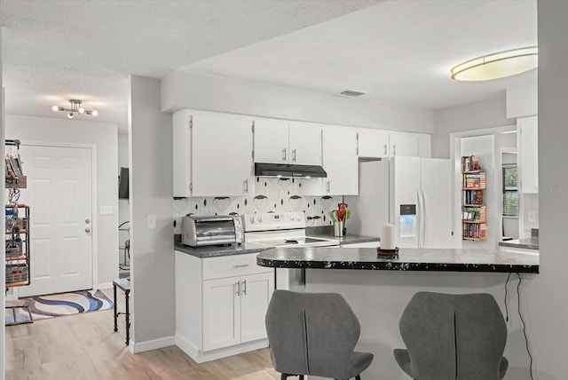 1608 Bomi Cir, Winter Park, FL 32792 - kitchen with white appliances, under cabinet range hood, a kitchen bar, white cabinetry, and light wood-style floors