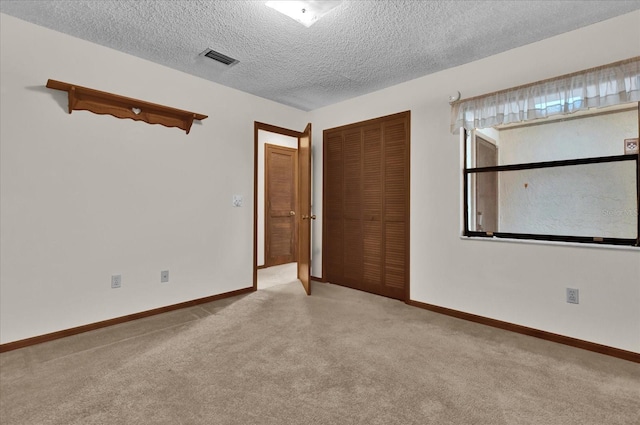 spare room with light colored carpet and a textured ceiling