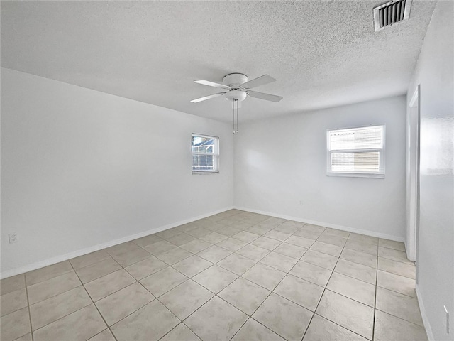 empty room featuring ceiling fan, light tile patterned floors, and a textured ceiling