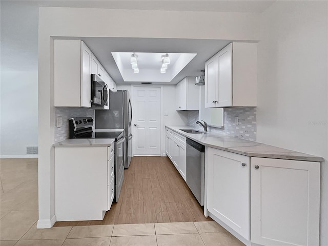 2448 S Daytona Ave, Flagler Beach, FL 32136 - kitchen featuring stainless steel appliances, a tray ceiling, white cabinets, light countertops, and decorative backsplash