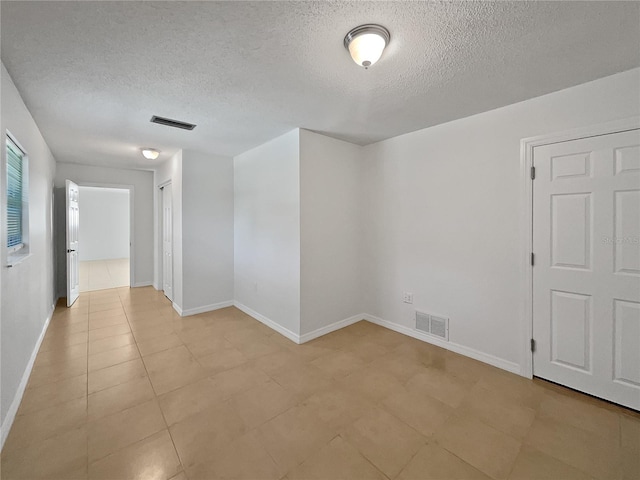 spare room featuring light tile patterned floors and a textured ceiling