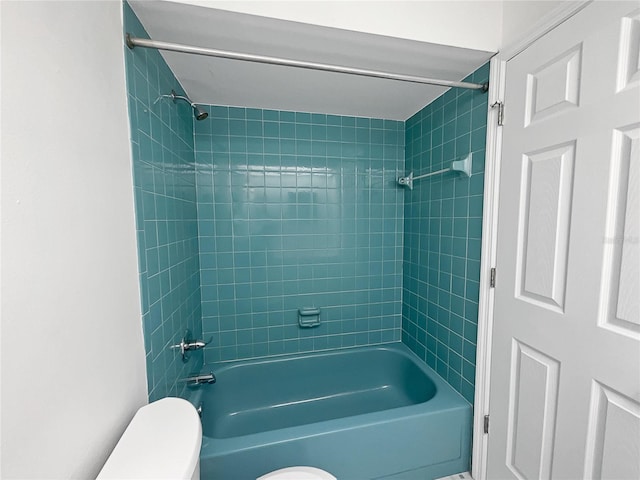 bathroom featuring toilet and tiled shower / bath