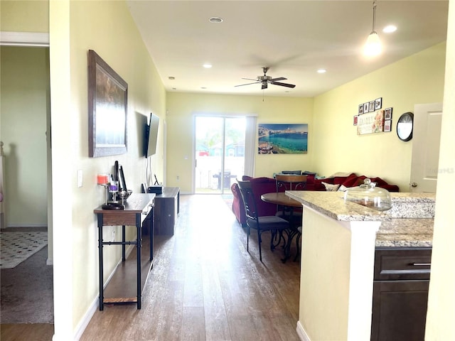 kitchen with light stone counters, dark brown cabinets, ceiling fan, decorative light fixtures, and hardwood / wood-style floors