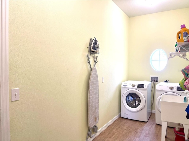 laundry room with washer and dryer, light hardwood / wood-style floors, and sink