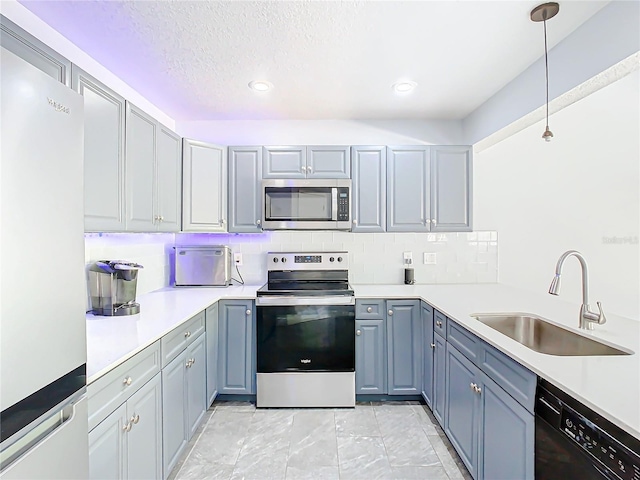 kitchen featuring a textured ceiling, decorative light fixtures, decorative backsplash, appliances with stainless steel finishes, and sink