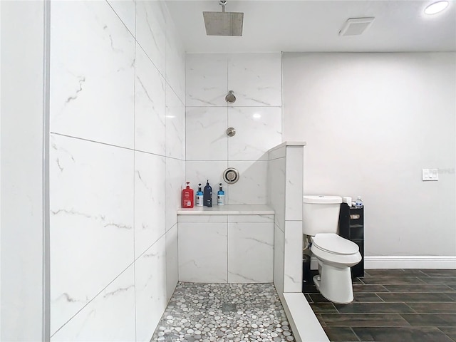 bathroom featuring toilet and tiled shower