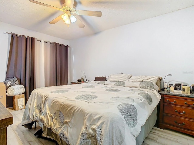 bedroom featuring ceiling fan, light wood-type flooring, and a textured ceiling