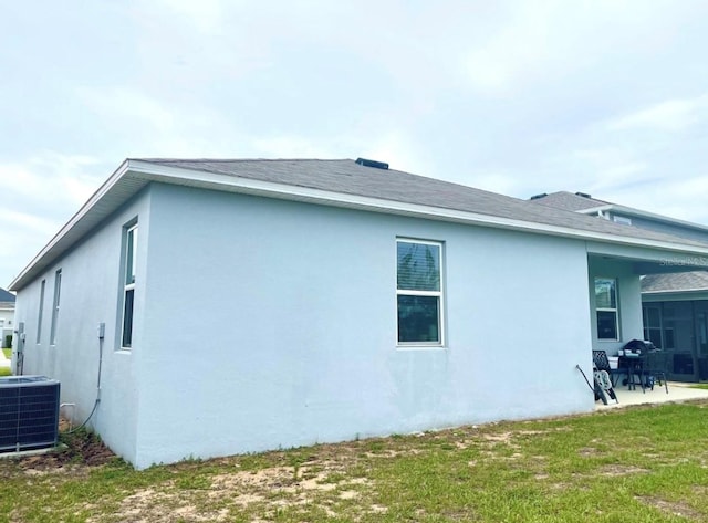 view of property exterior featuring central air condition unit and a lawn