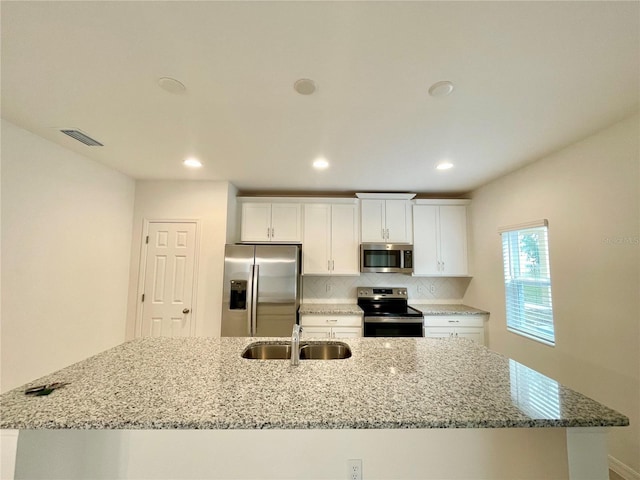 kitchen with white cabinetry, sink, stainless steel appliances, and light stone counters