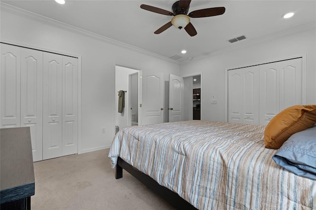 carpeted bedroom featuring two closets, ceiling fan, and crown molding