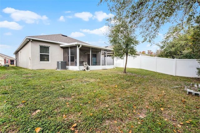 rear view of house with central AC unit, a lawn, and a sunroom