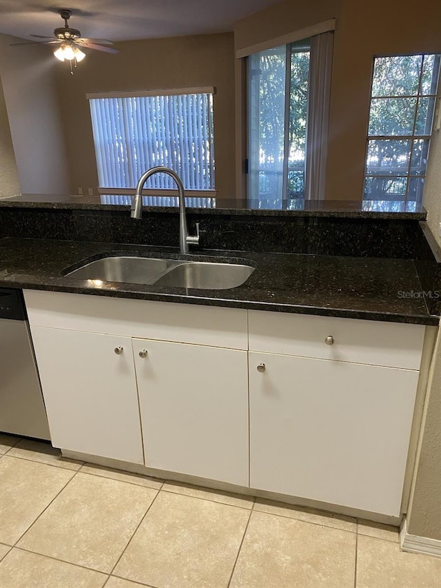 kitchen with dark stone countertops, dishwasher, sink, and white cabinets