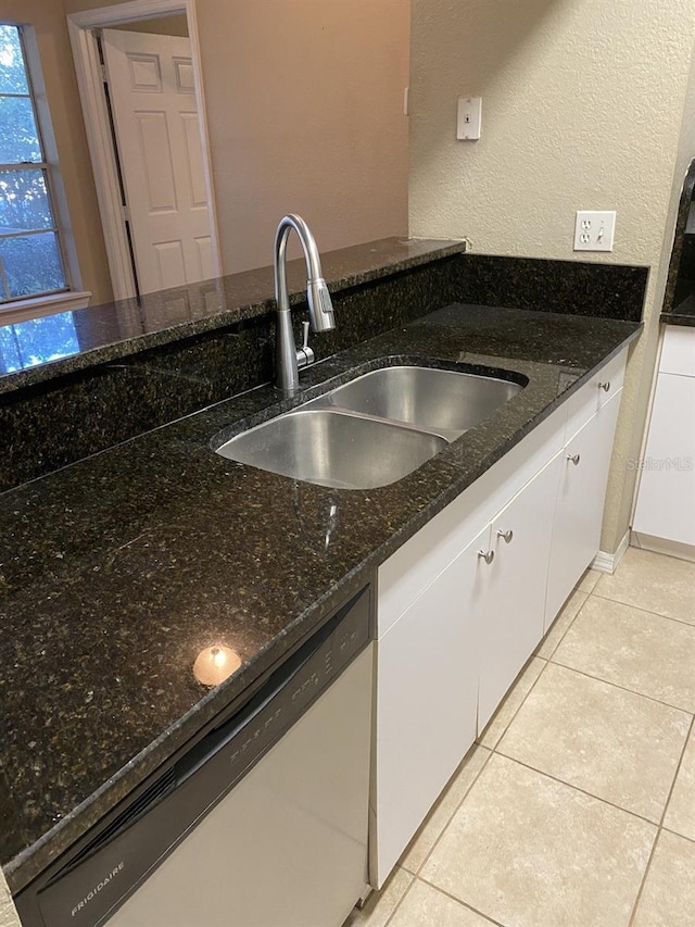 kitchen with sink, white cabinetry, stainless steel dishwasher, and dark stone countertops