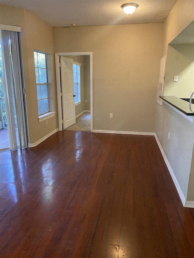 unfurnished dining area featuring dark hardwood / wood-style flooring and a textured ceiling