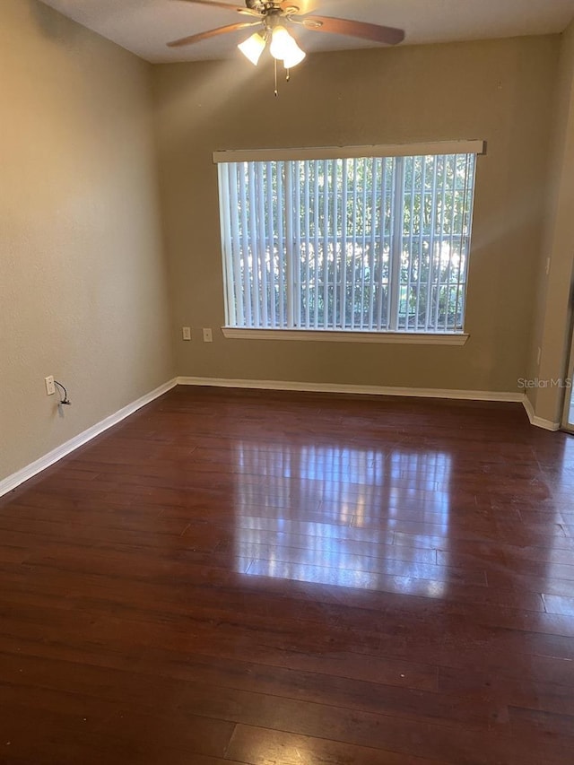 empty room with ceiling fan and dark hardwood / wood-style flooring