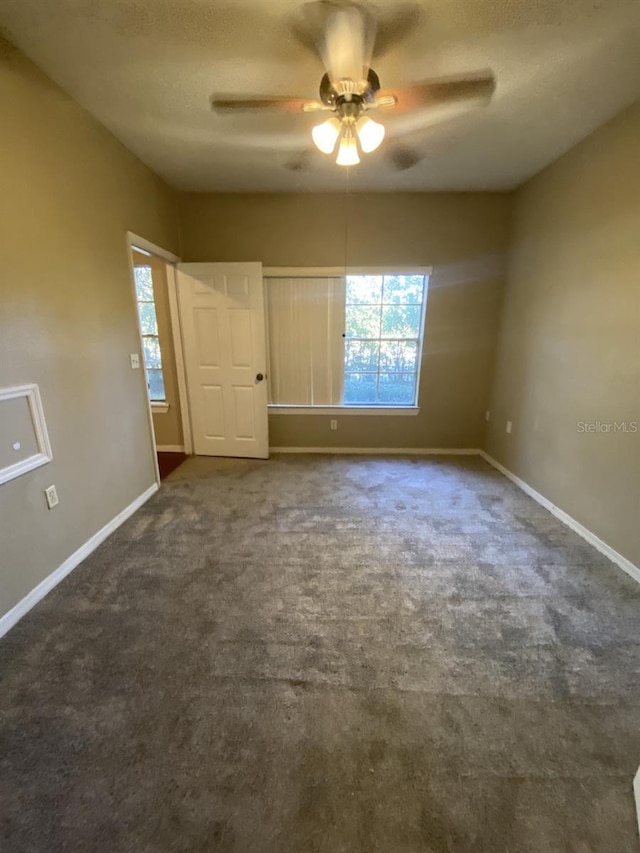 empty room featuring dark carpet and ceiling fan