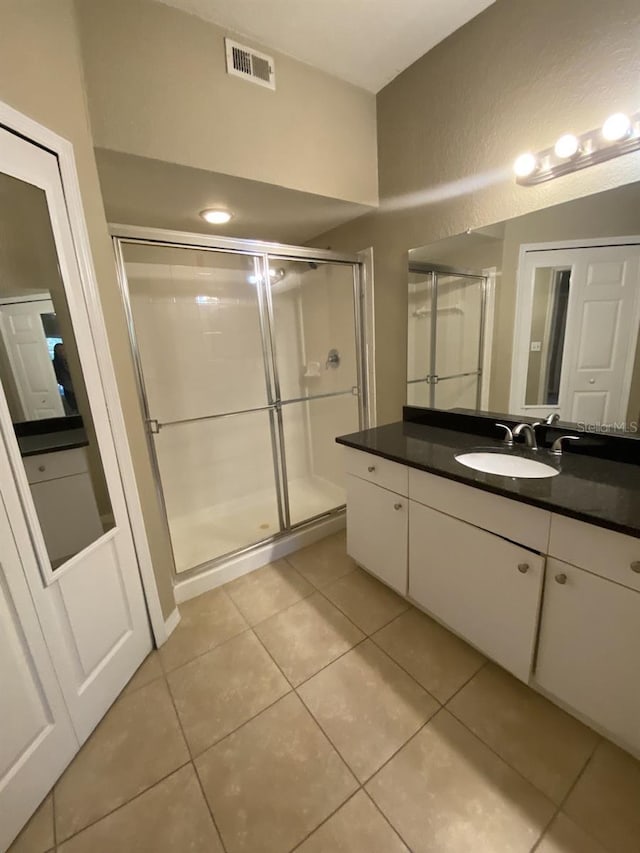 bathroom with tile patterned flooring, vanity, and a shower with door