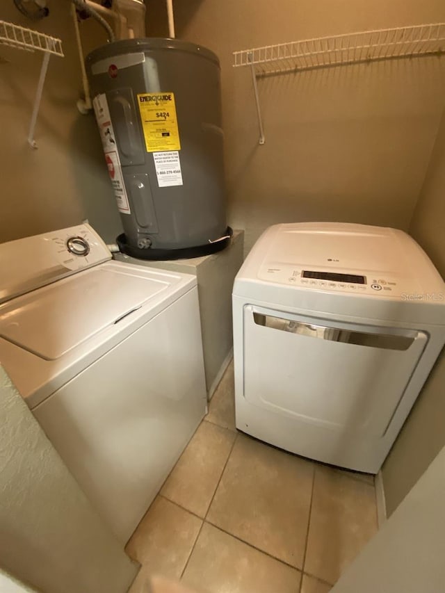 washroom featuring electric water heater, light tile patterned floors, and washing machine and clothes dryer