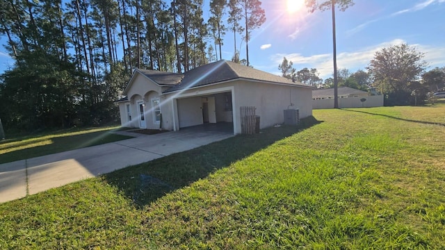 view of side of property featuring a lawn, a garage, and central AC