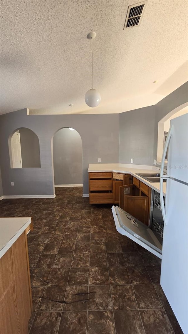 kitchen with white fridge, sink, a textured ceiling, and vaulted ceiling