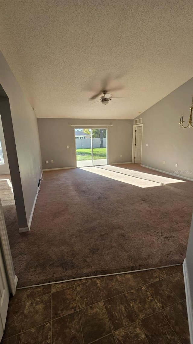 spare room with dark colored carpet, a textured ceiling, and vaulted ceiling