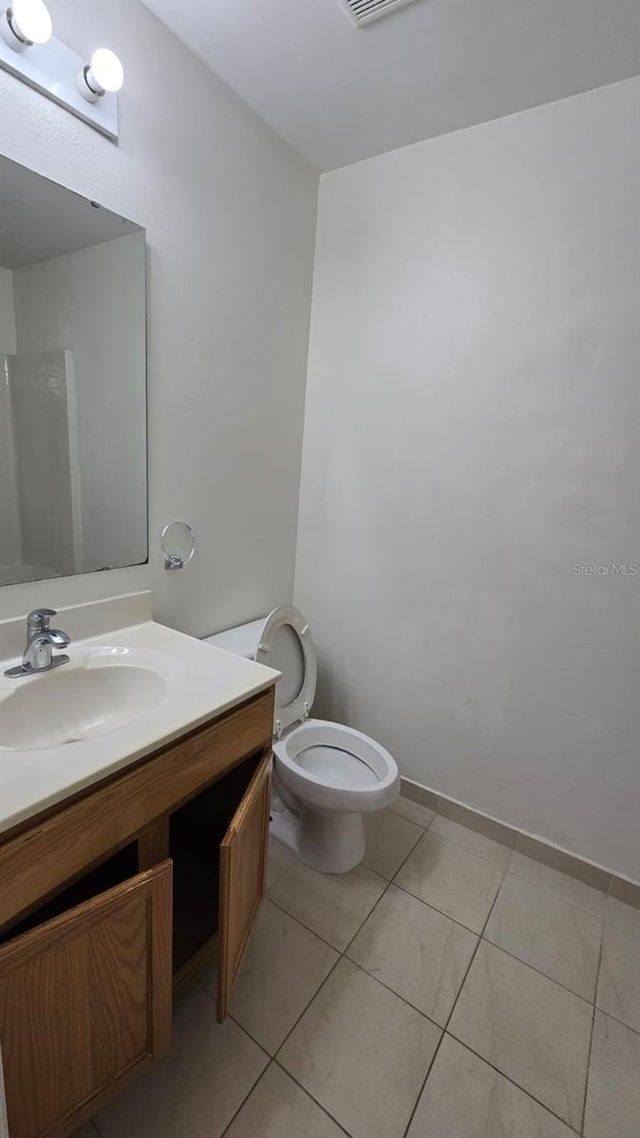 bathroom with tile patterned flooring, vanity, and toilet