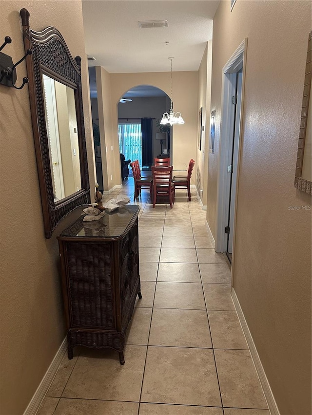 hallway featuring a chandelier and light tile patterned flooring