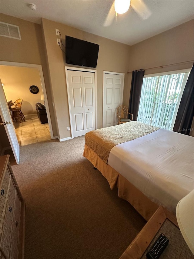 carpeted bedroom featuring ceiling fan and multiple closets