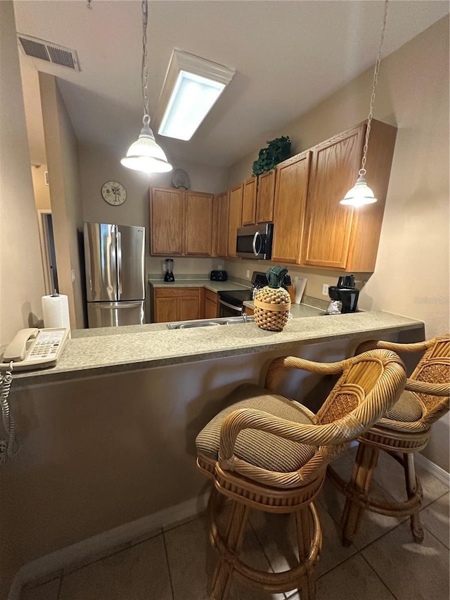 kitchen with kitchen peninsula, a breakfast bar, hanging light fixtures, and appliances with stainless steel finishes