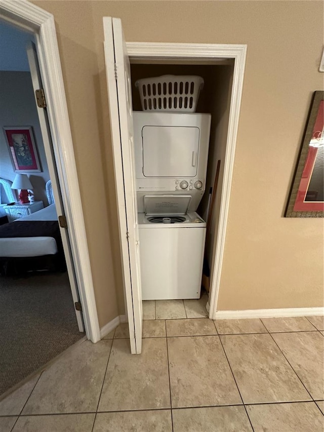 laundry room featuring light tile patterned flooring and stacked washer and clothes dryer