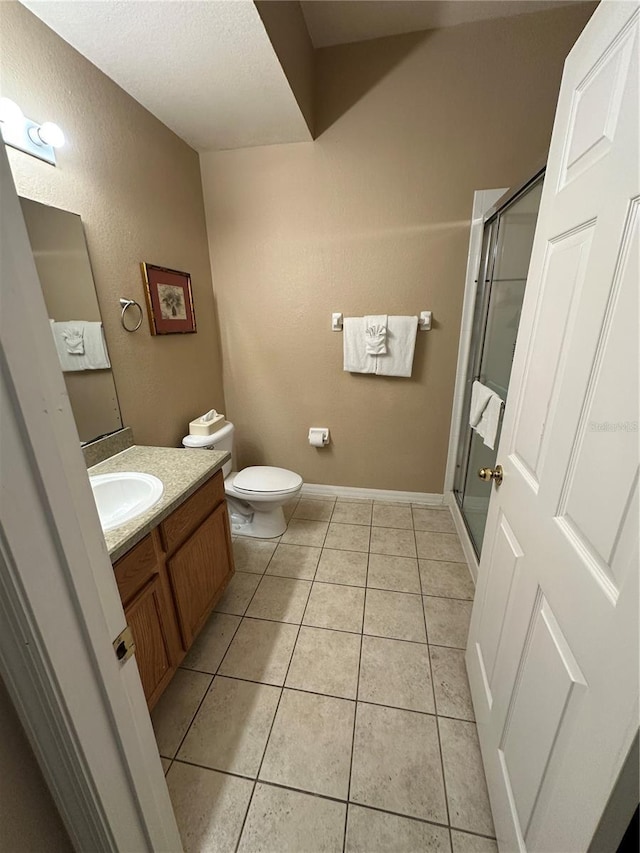 bathroom featuring tile patterned floors, vanity, an enclosed shower, and toilet