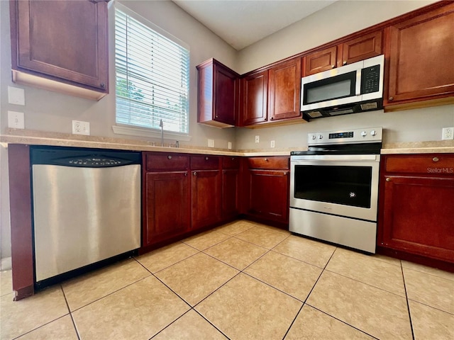 kitchen with a sink, stainless steel appliances, light tile patterned flooring, and light countertops