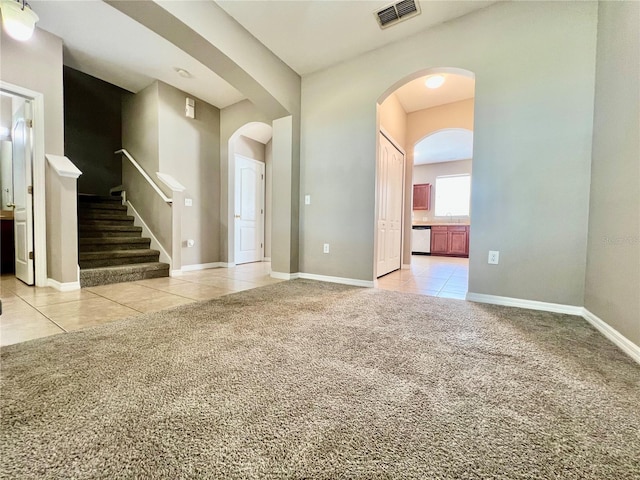 spare room with light carpet, visible vents, arched walkways, and light tile patterned floors