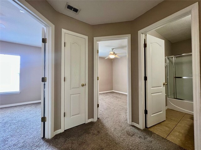 hall with visible vents, baseboards, and carpet