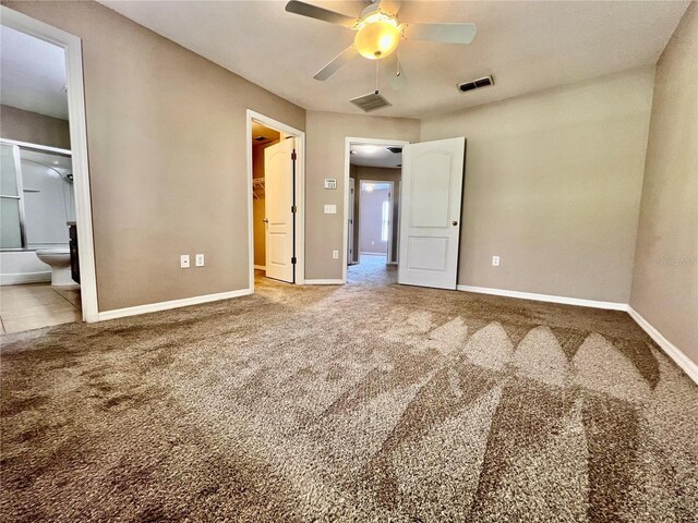 unfurnished bedroom with a walk in closet, carpet floors, baseboards, and visible vents