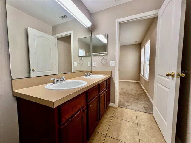 full bathroom with a sink, visible vents, double vanity, and tile patterned flooring