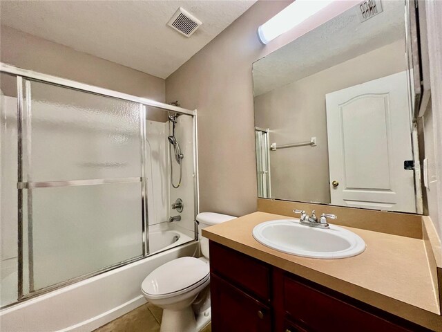 bathroom with visible vents, bath / shower combo with glass door, toilet, and vanity