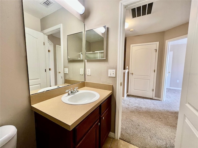 bathroom featuring visible vents, baseboards, toilet, and vanity