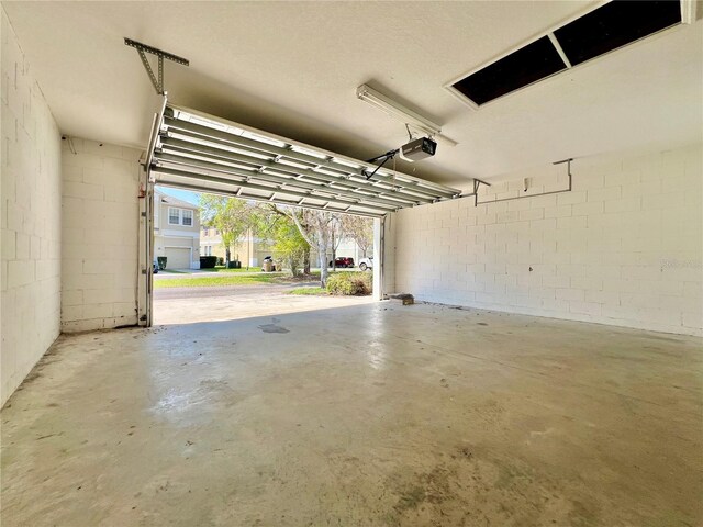 garage with a garage door opener and concrete block wall