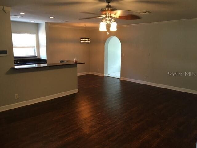 empty room with ceiling fan, ornamental molding, and dark wood-type flooring