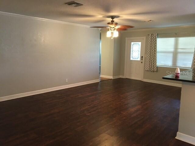 spare room with ornamental molding, ceiling fan, and dark wood-type flooring