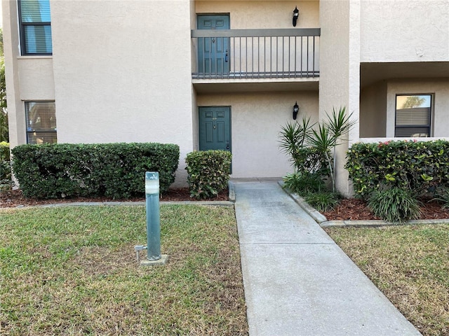 doorway to property with a lawn and a balcony