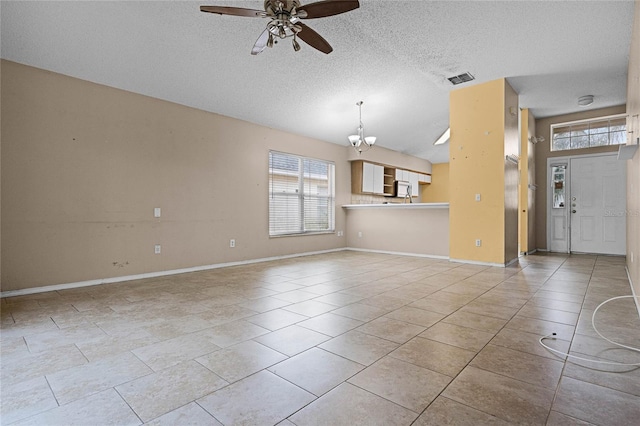 unfurnished living room with ceiling fan with notable chandelier, light tile patterned floors, and a textured ceiling