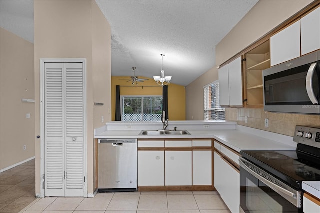 kitchen featuring stainless steel appliances, vaulted ceiling, sink, white cabinets, and light tile patterned flooring