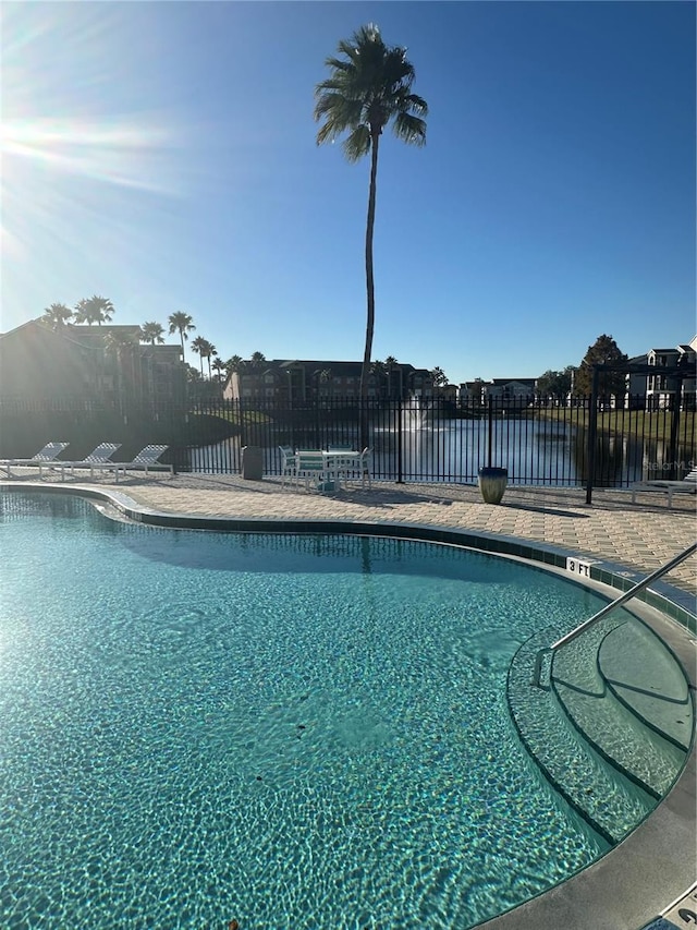 view of pool with a water view and a patio