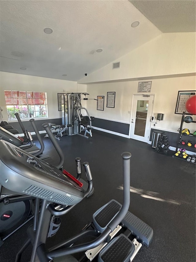 exercise room with a textured ceiling and vaulted ceiling