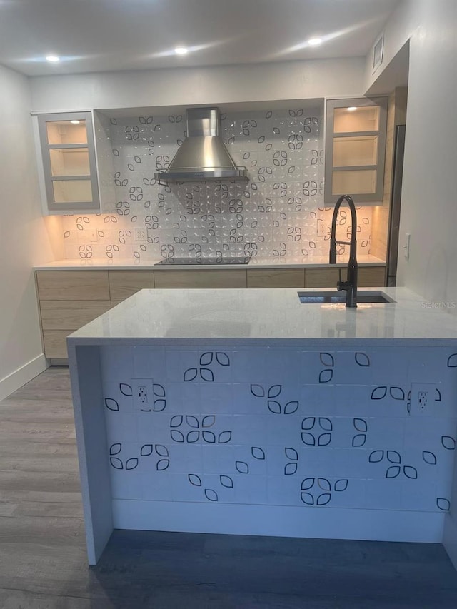 kitchen with decorative backsplash, light stone countertops, wall chimney exhaust hood, sink, and hardwood / wood-style floors