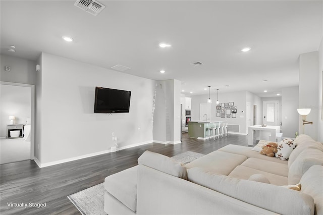 living area with recessed lighting, dark wood-style flooring, and visible vents