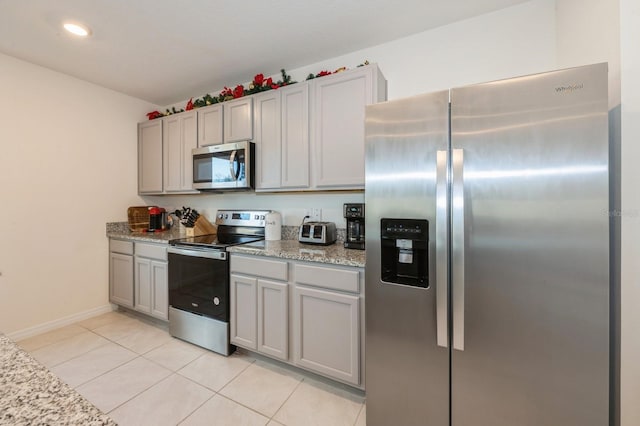 kitchen with light stone counters, light tile patterned floors, and appliances with stainless steel finishes